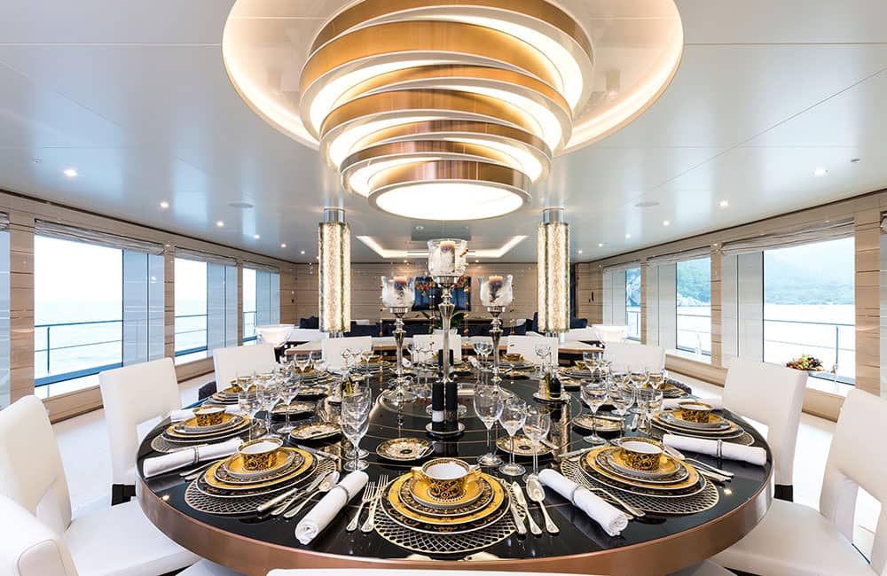 Dining room on yacht Irimari surrounded by windows with ocean views