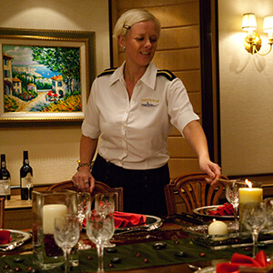 Yacht Stewardess lighting a candle at a dinner table