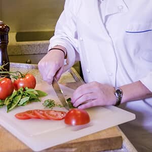 Yacht cook cutting tomato and basil