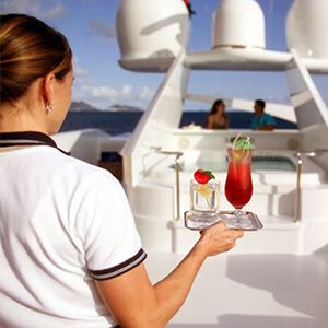 Yacht junior stewardess serving afternoon cocktails