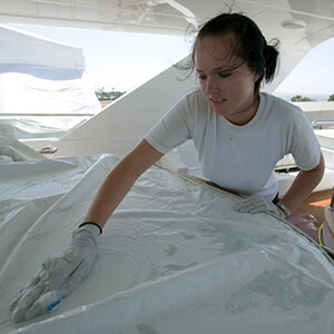Yacht stewardess or deckhand cleaning a tarp