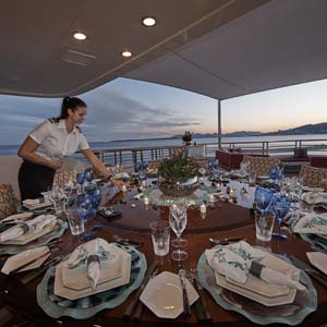 Yachts Stewardess setting a table for 12 at dusk